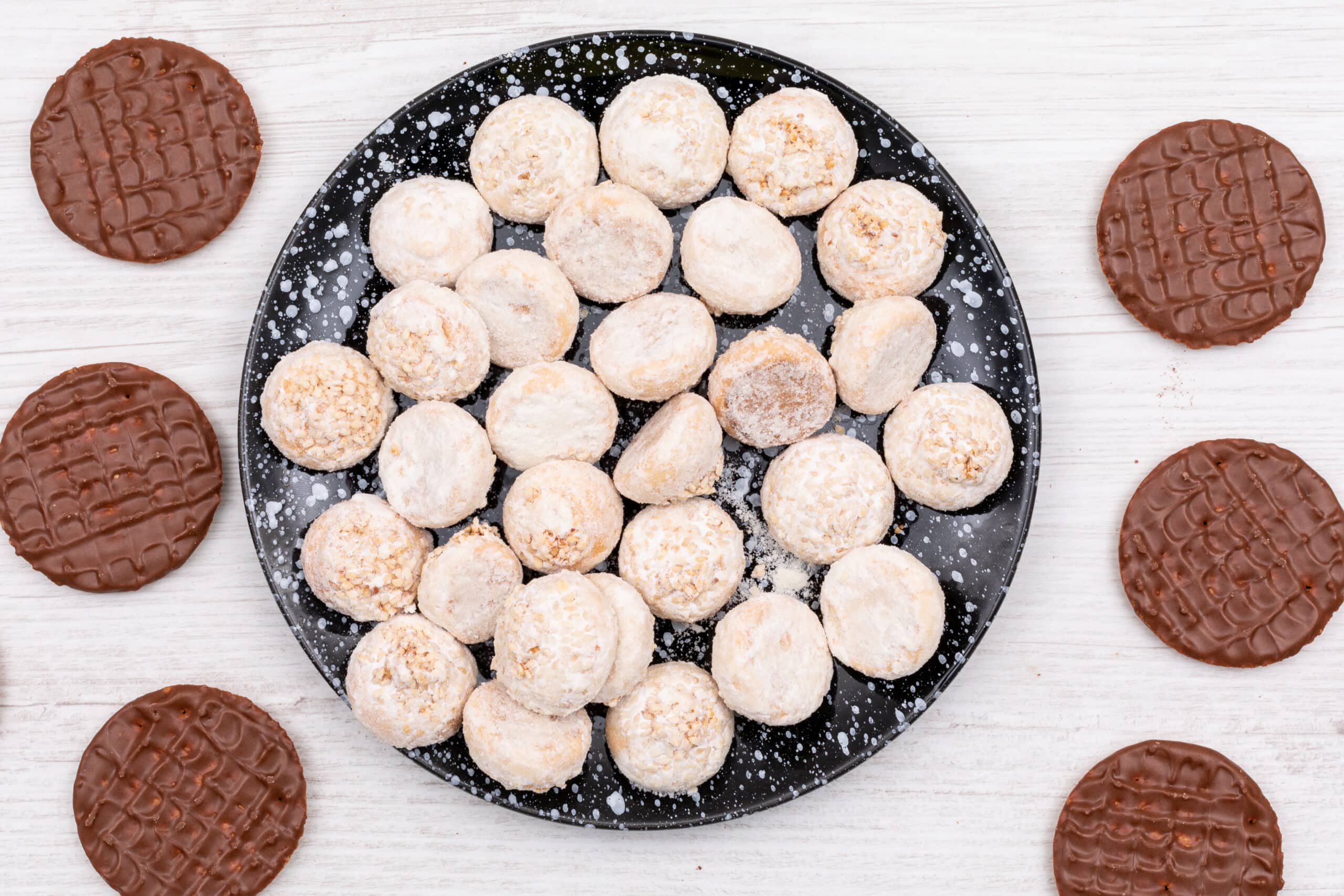Freshly baked chocolate chip snowball cookies dusted with powdered sugar, arranged festively on a holiday-themed plate
